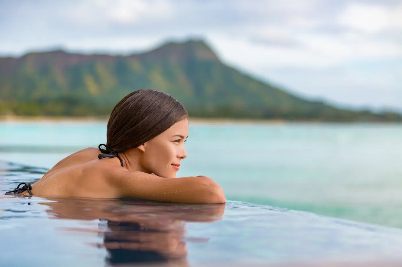 Woman relaxing at the edge of a serene coastal infinity pool