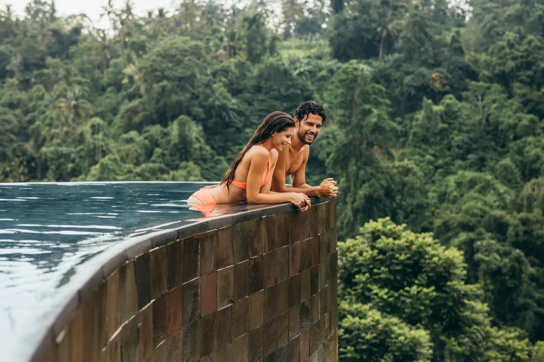 Couple relaxing at the edge of a mountain-view infinity pool